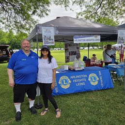Anam with a man in front of Arlington Heights Lion's table